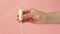 Female hand shows a tampon on a pink background.