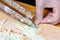 Female hand slicing leafs of fresh juicy white cabbage by stainless steel knife for shredding cabbage on the wooden cutting board