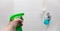 A female hand spraying cleaner into a white tiled shower