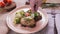 Female hand sprinkles baked fish with lentils with green onions in a beige plate.