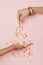 Female hand sprinkles gold confetti stars decoration on hand on pastel pink background. Celebration, Wedding,