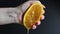 A female hand squeezes half of a fresh and juicy orange. Citrus orange juice dripping from orange pulp on a black background. The