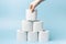 Female hand stacks toilet paper in a stack on blue background close-up