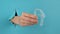 A female hand sticking out of a hole from a blue background holds removable night retainers.