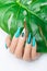 Female hand with stiletto nail design. Glitter cyan nail polish manicure. Female model hand with perfect manicure