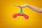 Female hand stuck to pink retro telephone receiver with sticky slime on yellow background.