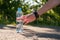 Female hand takes the bottle with cool drinking water, standing on the asphalt road on a sunny summer day.