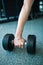 Female hand taking dumbells from row of barbells in gym