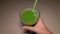 Female hand taking fresh green celery juice in glass with straw. Antioxidant vegan plant based diet for cleansing body