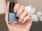 Female hand with thermal blue nail design holding nail polish bottle