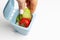 Female hand throws food garbage in trash can on white background