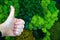 Female hand with thumb up as super symbol on green decorative moss background, eco design concept