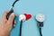 Female hand, tonometer, stethoscope and heart on a blue background. The concept of health, the measurement of pressure, heart dise