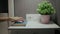 Female hand turn off an alarm clock on mobile phone on bedside table with indoor plant and book