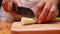 Female hand using kitchen knife to cut Japanese Long Onion or Japanese Scallion or Green Onion on wooden cutting board. Woman is p