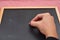 Female hand wants to write something on blackboard with chalk