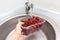 Female hand washing ripe sweet cherry in a kitchen sink under water jet, cleaning fresh fruits of bacteria and dirt