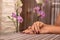 Female hand with wine color nails polish on a desk in beauty studio and blurred floral background