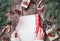 Female hand wraps Christmas gift on holiday wrapping on wooden background with Fir branches, pine cones, red decorations