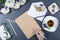 Female hand writing on a sheet of brown craft paper. Fresh chrysanthemums, pencils, envelope with note and flower, cup of tea and