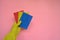 Female hand  in yellow rubber glove with colored washcloths on pink background. Cleaning or housekeeping concept background.