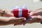 Female hands accept a gift from male hands. on the street they give a red box, a white bow. holiday concept, surprise