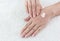 Female hands applaing a cream on fabric background