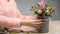 Female hands arrange lace bow at box with flowers