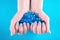 Female hands with blue manicure on finger nails holding many decorative gemstone