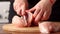 Female hands chef cutting raw chicken meat breast.