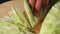 Female hands chopped cabbage on wooden board, close-up.