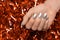 Female hands with Christmas nail design. Silver nail polish manicure. Female hand on orange New Year tinsel background