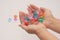 Female hands clasped hold multi-colored glass pebbles on a light background.  Jewelry and toys for women and children.