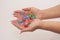 Female hands clasped hold multi-colored glass pebbles on a light background.  Jewelry and toys for women and children.