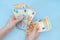 Female hands counting stack of euro banknotes on blue background. Money. Business. Finance