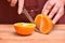 Female hands cut knife orange, juicy and ripe