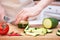 Female hands cut with a knife a young seasonal zucchini into strips on a wooden cutting board. The method of preparation of