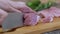 Female Hands Cuts Raw Pork Meat with a Sharp Knife on a Cutting Wood Board. Zoom