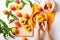 Female hands cutting fresh sweet peaches. Peaches whole fruits leaves, half peach, peach slices on white wooden kitchen table.