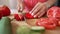 Female hands cutting red pepper slicing vegetable in slow motion with knife. Unrecognizable Caucasian woman preparing
