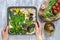 Female hands decorating raw floral painting focaccia, garden sourdough art with seasonal wild garlic leaves.