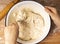 Female hands and dough in a white metal bowl, top view