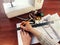 Female hands draw with a pencil and a ruler on white paper against the background of a sewing machine and accessories, close-up.