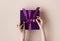 Female hands with festive minimalistic manicure tie a bow on violet gift box. Christmas Eve concept.