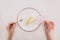 Female hands, flower and piece of cake on plate on white tabletop