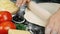 Female hands are forming dough on floured black table and rolling out with rolling pin. Baker rolls pizza dough on table before ba