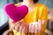 Female hands giving pink heart pillow and make a symbol of heart love with fingers.