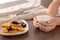 Female hands with glass of delicious milk and plate with waffles on wooden table