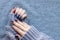 Female hands in gray knitted sweater with beautiful manicure - dark blue glittered nails on knitted background with copy space