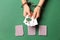 Female hands in handcuffs holding playing cards on color background